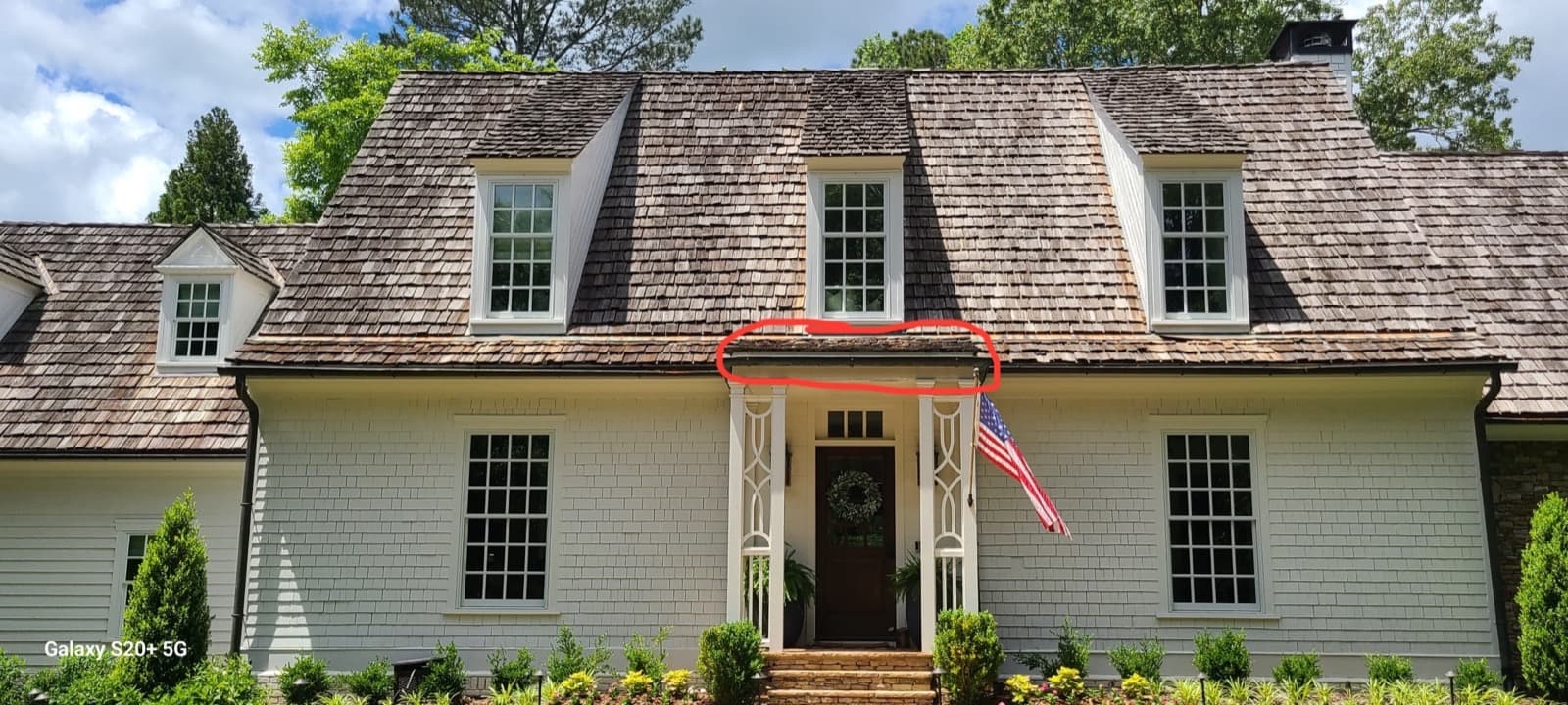 Cedar shake roof assessment with marked problem area above a residential entry